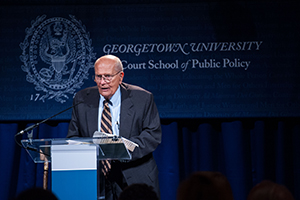 John Dingell at podium with Georgetown University McCourt School of Public Policy behind him