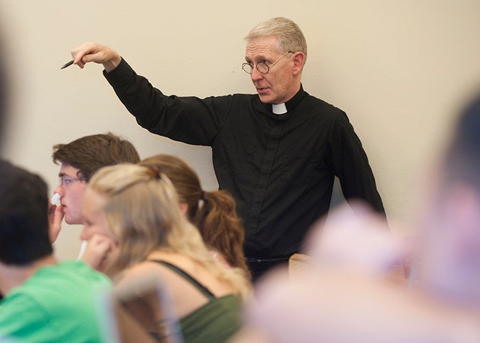 Rev. Dennis McManus gestures while teaching students in class at Georgetown.