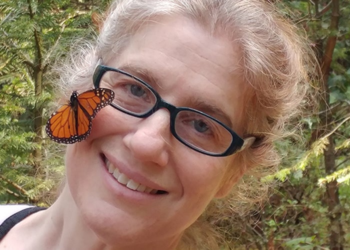 Leslie Ries, wearing glasses outside with butterfly on her cheek