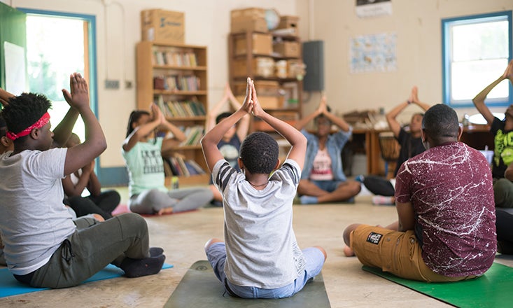 students in a circle in a classroom doing yoga poses