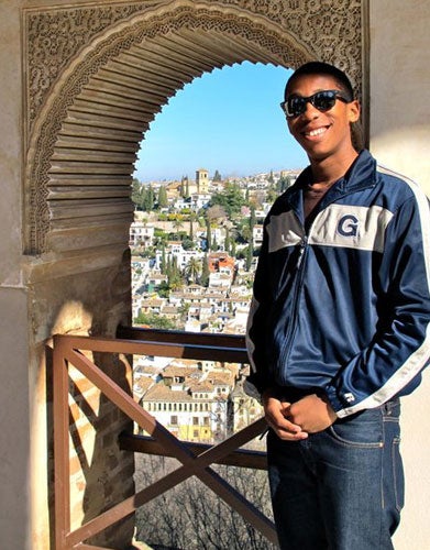 VON’TRAVIS DEJANARO CRAWFORD wearing Georgetown jacket in archway with buildings in view in Spain 