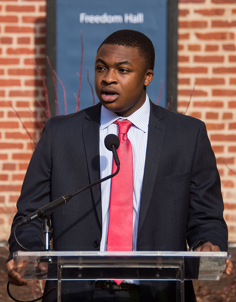 Ayodele Aruleba (C’17) at podium in front of building reading "Freedom Hall"