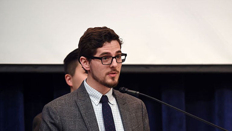 Andrew Schneider speaking at a podium