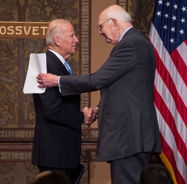 Vice President Joe Biden and Paul Volcker shake hands on stage in Gaston Hall.