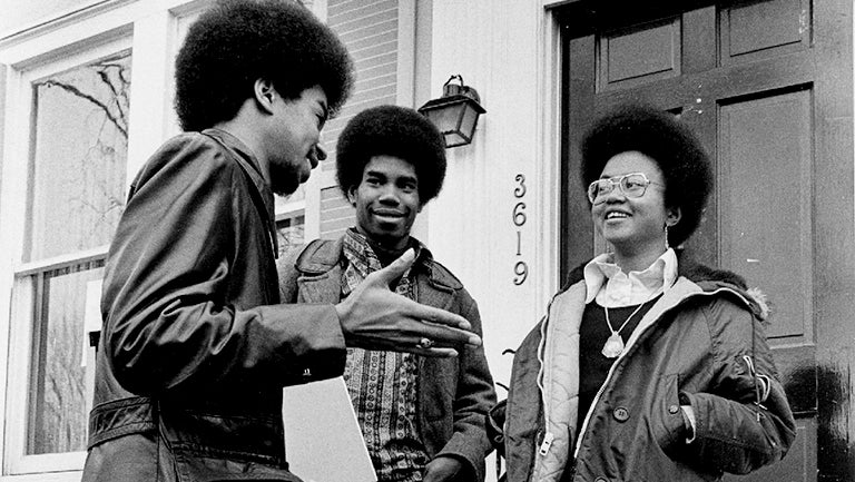 A black and white photo from the late 1960s or early 1970s shows three students standing outside the Black House, located at 3619 O St. NW.