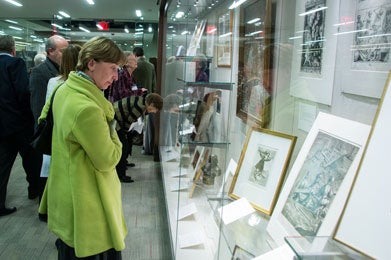 A woman in a green coat views an exhibition called Treasures Since 2000.