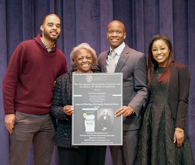 Marcus Board, Carol Anderson, Robert Patterson and Linda Blair pose together as Carol Anderson and Robert Patterson hold up the poster promoting her lecture.