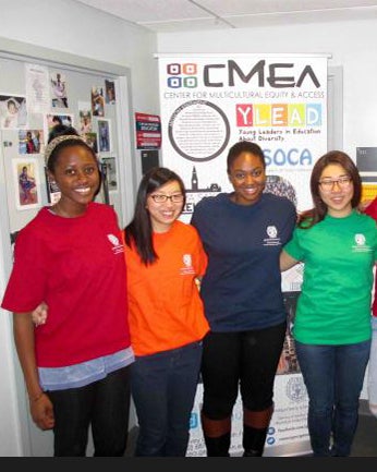 Four CMEA Spring 2016 interns dressed in colorful shirts pose in front of a poster.