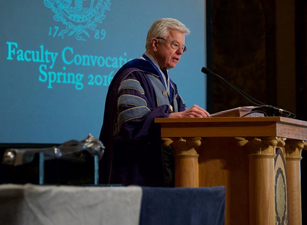 Tom Beauchamp speaking at Podium behind a screen that reads "Faculty Convocation Spring 2016"