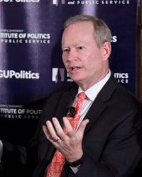 Mick Cornett sits while speaking in front of GU Politics background