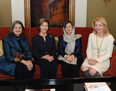 Phyllis Magrab, Laura Bush, Rula Ghani and Catherine Russell, seating on sofa with abstract painting behind them