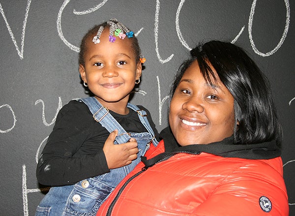 Crystal Jenkins holds her daughter in her arms in front of a chalkboard.