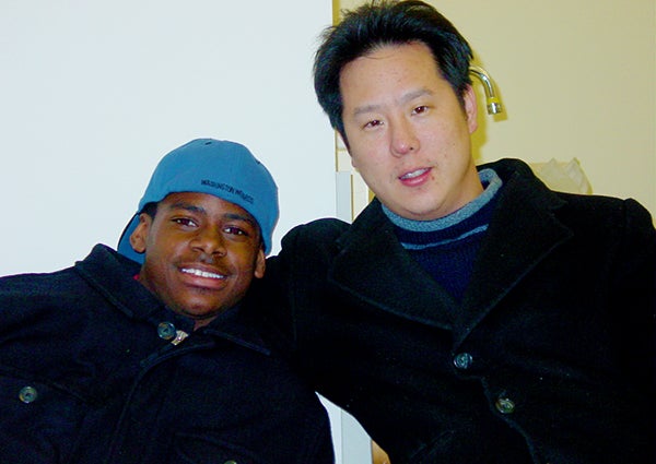 Dwaine Brown leans in close for a half hug with Steve Park as they pose for a photo inside a room.