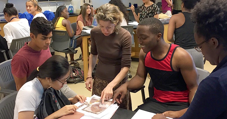 Students gather around professor Heidi Elmendorf in the science lab as she helps them with an assignment.