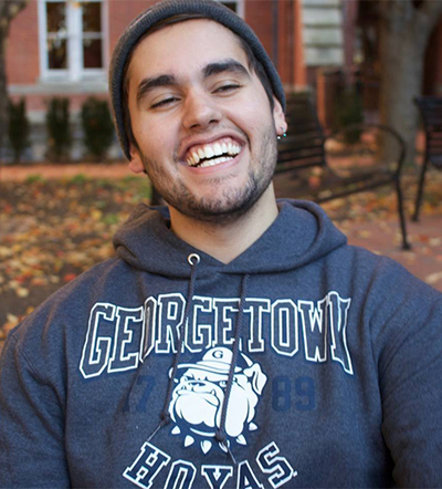 Emilio Joubert laughs on campus wearing a Georgetown Hoyas sweatshirt.