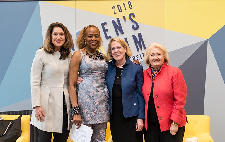 Jane Aiken, Rosemary Kilkenny, Judith Areen and Melanne Verveer pose in front of the 2018 Women's Forum sign.