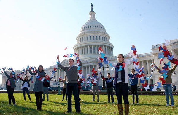 Students stand on the Capitol lawn with the Capitol building in the background holding up paper butterflies in support of Dreamers.