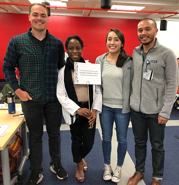 Matt Triano, Toyosi Ipaye, Hailey Roumimper and Francis Navarra pose together with a GUSOM Generation I sign.