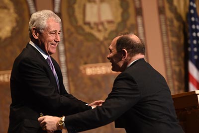 Robert McDonald shakes hands with Chuck Hagel as he walks on stage in Gaston Hall