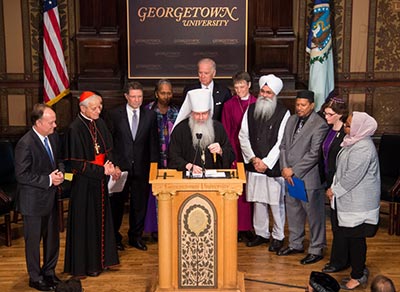 Religious leaders join Vice President Joseph R. Biden Jr. and Georgetown University President Jack J. DeGioia in prayer on stage in Gaston Hall.
