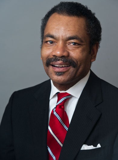 Professor Maurice Jackson, in a red-striped tie, smiles for the camera in a headshot. 