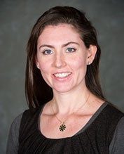 Anna Johnson smiles against a gray background. 