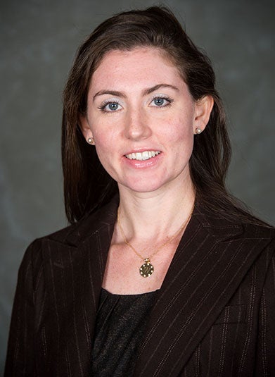 Anna Johnson, dressed in a brown suit, smiles in a headshot.