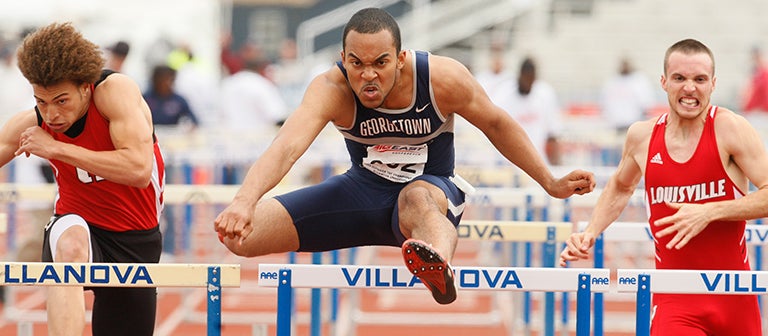 This 2008 photo shows Christopher Kinney clearing a track hurdle as two competitors close in on him during a race.