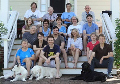 Dean Lancaster sits on some steps with her extended family and three dogs.