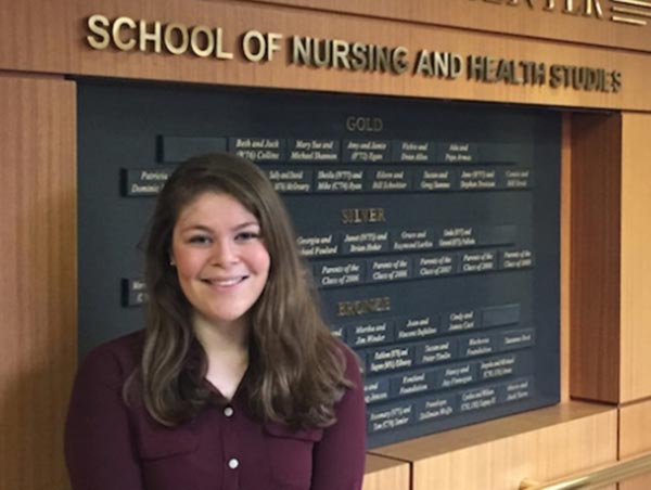 Jennifer LaPier stands in front a sign reading "School of Nursing and Health Studies"