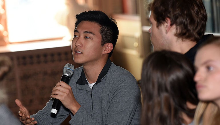 Seated student with microphone with other students seated nearby