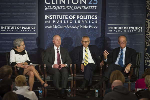 Judy Feder, Mack McLarty, John Podesta and Erskine Bowles sitting onstage with Clinton 25 banner behind them