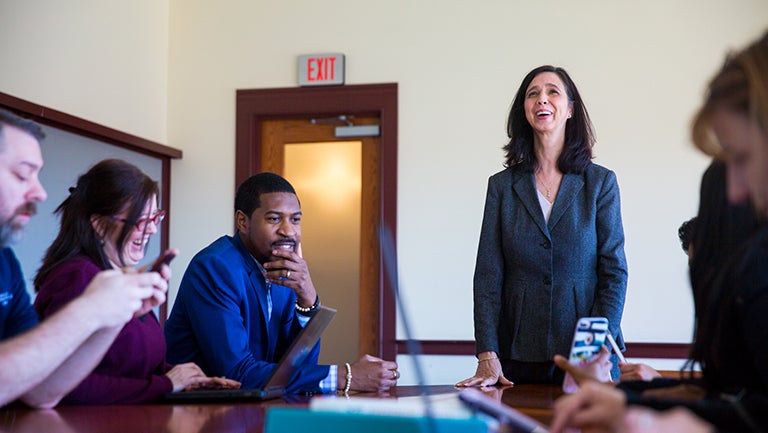 Jeanine Turner standing with students sitting at a table ignoring her and using their phones and laptops