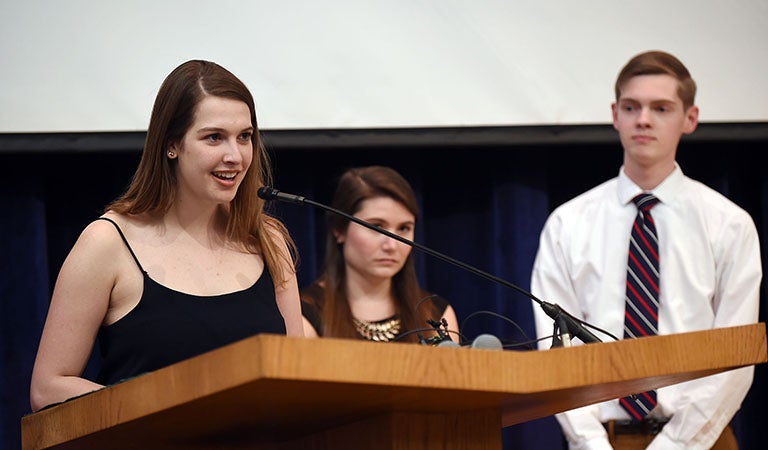 Jessica Scoratow, Mattie Haag and Alex Feltes on stage with Jessica speaking into microphone