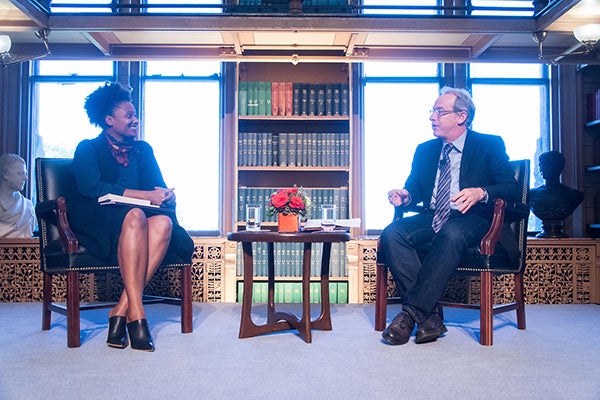 Tracy K. Smith and Paul Elie sitting in chairs in front of large windows in Riggs Library