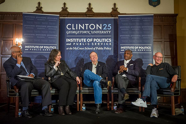 Mo Ellithee, Mandy Grunwald, Paul Begala, Rodney Slater and James Carville sitting onstage in front of Clinton 25 banner