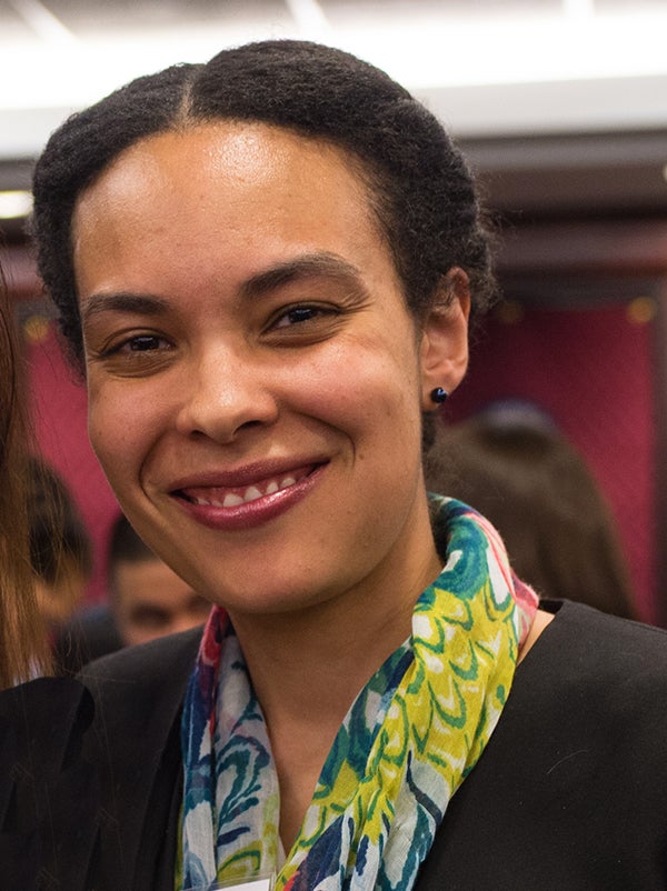 Headshot of LeNaya Hezel with people and a red wall in the background.