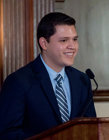 Luis Gonzalez smiles as he speaks into the microphone at the lectern in Copley Formal Lounge.