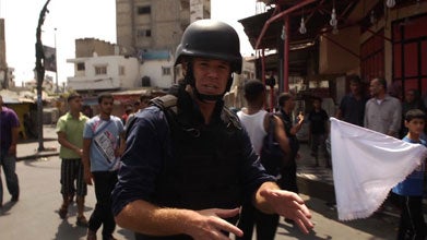 Alex Marquadt, in a helmet, walks in a crowded street.