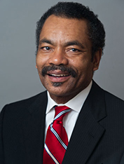 Maurice Brown, in a suit and tie, smiles in a headshot.