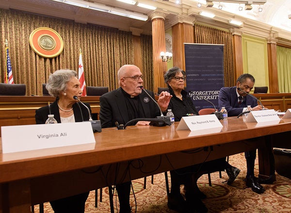 Rev. Raymond Kemp talks during a panel discussion with Virginia Ali and Charlene Drew Jarvis sitting on each side of him listening as Maurice Jackson sits to the far right listening and writing.