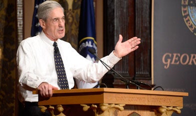 Robert Mueller speaks behind a podium on Gaston Hall's stage.