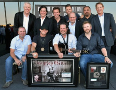 Georgetown alumnus Jim McCormick sits next to country music singer Brantley Gilbert, second from left, while posing with members of the record label, management and publishing teams.
