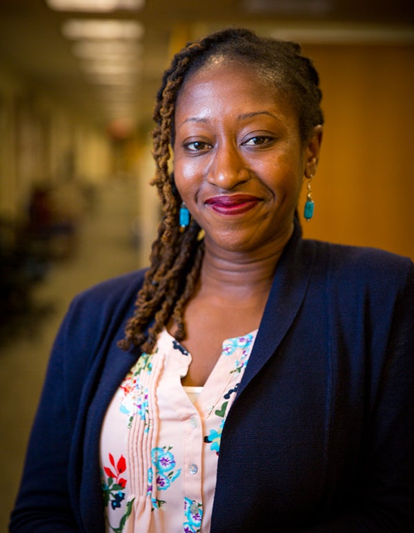 Rosemary Ndubuizu smile into the camera with an office hallway in the background.