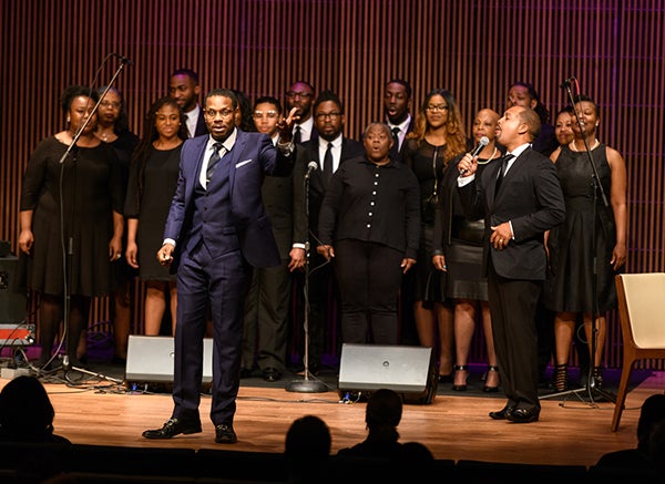 Nolan Williams Jr. leads the audience in song as a group of singers performs on stage behind him.