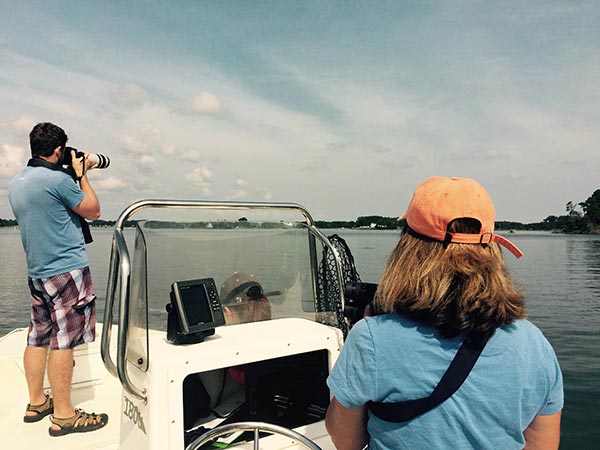 Janet Mann stands behind the boat's steering wheel as a student takes photographs of dolphins in the Potomac River.