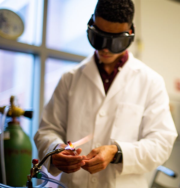 Orlando Stewart works in the chemistry lab using a flame to heat materials. 