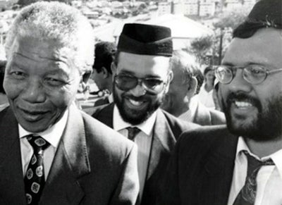 Ebrahim Rasool stands behind Nelson Mandela at an event in South Africa.