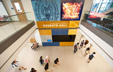 An overhead shot of Regents Hall depicts students with backpacks walking through the building.