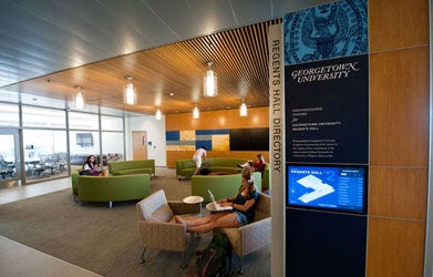 A photo of Regents Hall depicts students studying and working on green couches.